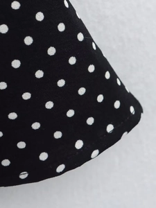 Detailed close-up of white polka dot pattern on black fabric with clean stitched hemline