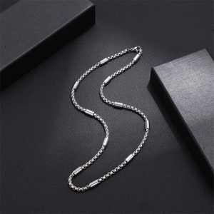 Polished stainless steel box chain necklace with cylinder beads on black background