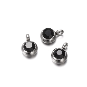 Detail of three stainless steel round pendants with black faceted zircon stones