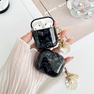 Detail of black marble pattern AirPods case with golden pearl and shell keychain