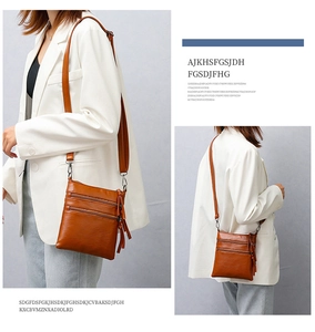 Detail of brown faux leather crossbody bag with three zipper layers and stylish fringe tassel