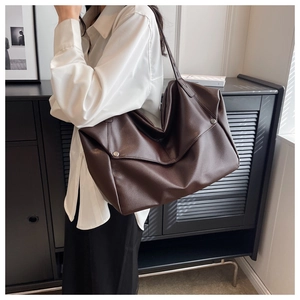 Detail of dark brown leather tote bag with metal rivet accents on the side and a spacious design