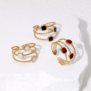Detailed view of triple-layered gold rings with colorful enamel square accents on stone