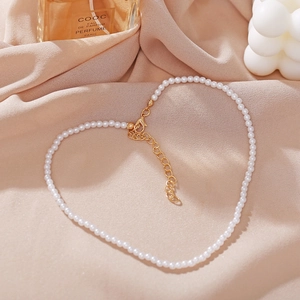 Macro shot of faux pearl necklace with gold lobster clasp arranged in heart shape