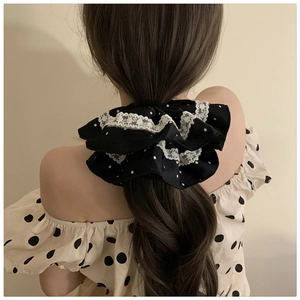 Detail of vintage polka dot scrunchie with lace edge worn on a ponytail hair