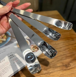 Close-up of four stainless steel dessert spoons held over a wooden table setting