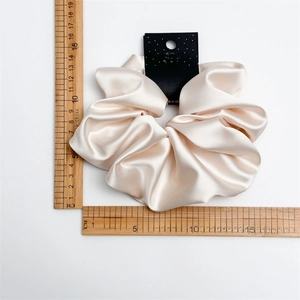 Close-up of champagne gold satin scrunchie with size measurement and handmade tag