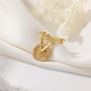 Golden bicycle pendant necklace with sparkling zirconia on white satin fabric
