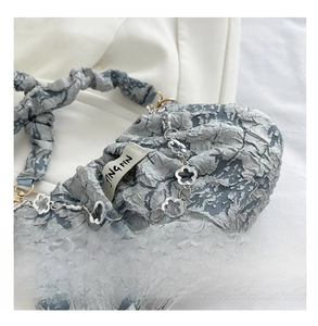 Detail of grey pleated fabric texture with decorative silver floral chain and brand label
