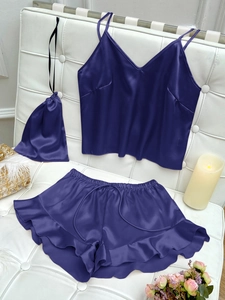 Detail of purple silk pajama set with camisole top and ruffled shorts on leather sofa