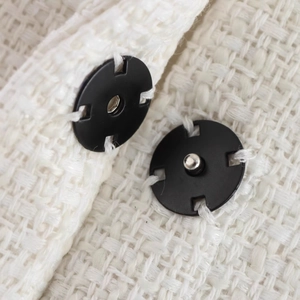 Front view of a white tweed cloak jacket featuring premium black metal snap buttons