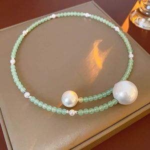 Detail of light green jade beads and large white pearls on a leather jewelry box