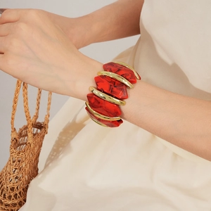 Gros plan de blocs de résine rouge marbré et maillons dorés sur un bracelet élégant