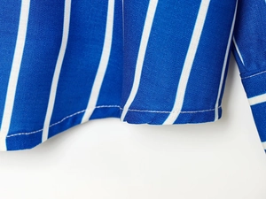 Vue macro des coutures précises et du tissu rayé bleu et blanc sur l'ourlet de la chemise
