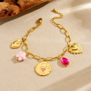 Detail of gold-plated bracelet with pink heart, floral charms and red gemstone pendants