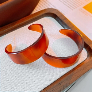 Macro shot of retro amber tortoiseshell resin C-shaped earrings on a fabric tray