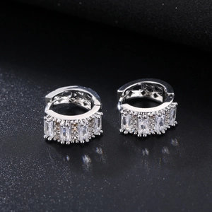Close-up of silver huggie earrings with baguette-cut and round cubic zirconia stones