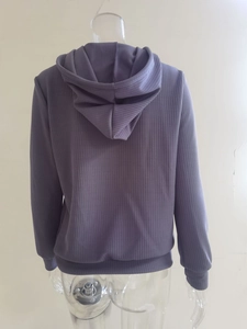 Detalle de sudadera morada con capucha a rayas y puños acanalados en el dorso