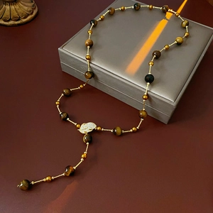 Detailed view of tiger eye bead long tassel necklace with golden leaf zircons