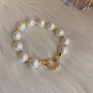 Detail of elegant gold-plated pearl bracelet with a sparkling zircon-encrusted clasp