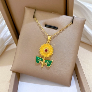 Detailed close-up of sunflower pendant with yellow enamel and red center gem on gold chain