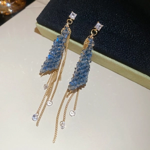 Macro shot of silver needle tassel earrings with blue crystals on black velvet