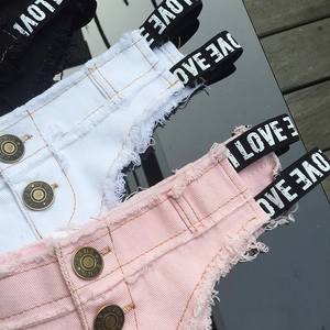 Dettaglio di pantaloncini in denim colorati con cinturini logo e bottoni metallici