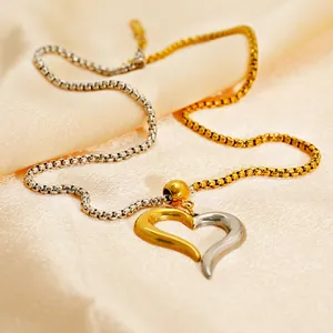 Two-tone heart pendant necklace in 18K gold plated stainless steel on silk background