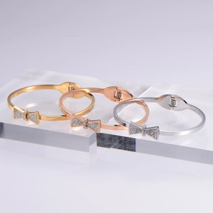 Bow-shaped crystal bangle in gold rose-gold and silver colors on acrylic blocks