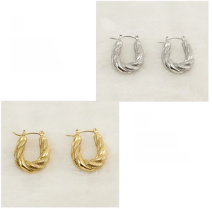 Detail showing polished gold and silver twisted U-shape stainless steel earrings