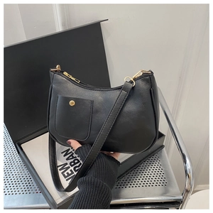 Detail of a black faux leather shoulder bag with gold hardware and a front snap pocket