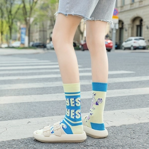 Detail of asymmetric cotton socks with stripes and graffiti worn with platform sandals