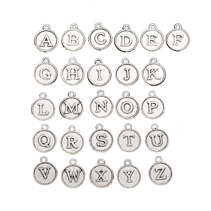 Detailed view of 26 silver alloy alphabet pendants for DIY jewelry crafting on white