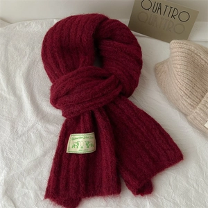 Thick burgundy knitted wool scarf with ribbed texture and vintage patch for winter warmth