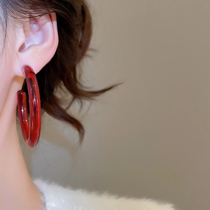 Side view of model wearing a large transparent amber red resin C-shape hoop earring