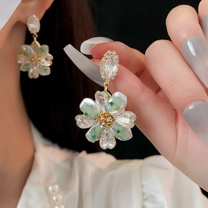 Vue macro des boucles d'oreilles en fleur avec pétales verts et clous en zircon