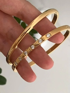 Detail of two-piece stackable gold-plated bangles with one smooth and one zircon-set band