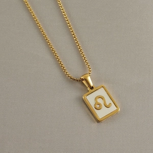 Macro shot of 18k gold plated stainless steel square white shell Leo zodiac pendant