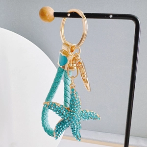 Macro detail of starfish keychain with turquoise rhinestones and braided leather cord