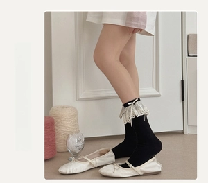 Detail of black calf socks with white lace trim and ribbon bow in balletcore style