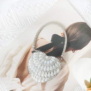 Detail of heart-shaped evening bag featuring white pearls and silver rhinestones on a magazine
