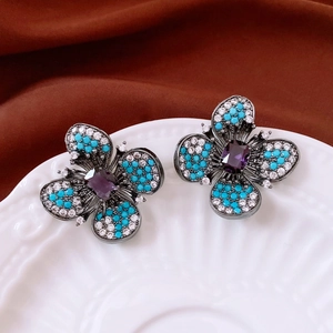 Détails macro de boucles d'oreilles papillon vintage avec pierre mauve et perles
