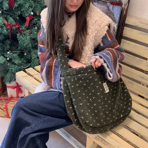 Close-up of olive green plush tote bag with white polka dots in a festive Christmas setting