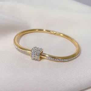 Detailed macro of gold-plated bangle featuring a sliding crystal-encrusted cylinder detail
