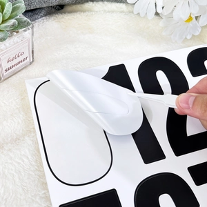 Detail view of applying black vinyl 4-inch mailbox numbers using a plastic peeling tool