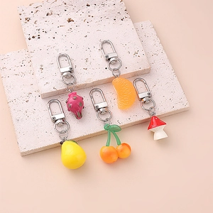 Detailed view of colorful resin fruit keychains with metal lobster clasps on stone