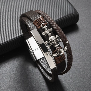 Detail of multilayer brown leather bracelet with silver skull and anchor charms