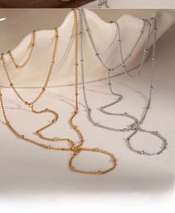 Detail of gold and silver beaded hand back chains on white ceramic display stand