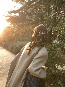 Leopard print scrunchie worn on a high ponytail with a khaki wool coat in warm sunset