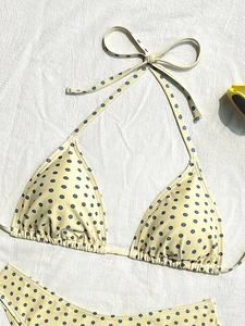 Dettaglio di bikini giallo a pois con occhiali da sole su tessuto bianco testurizzato